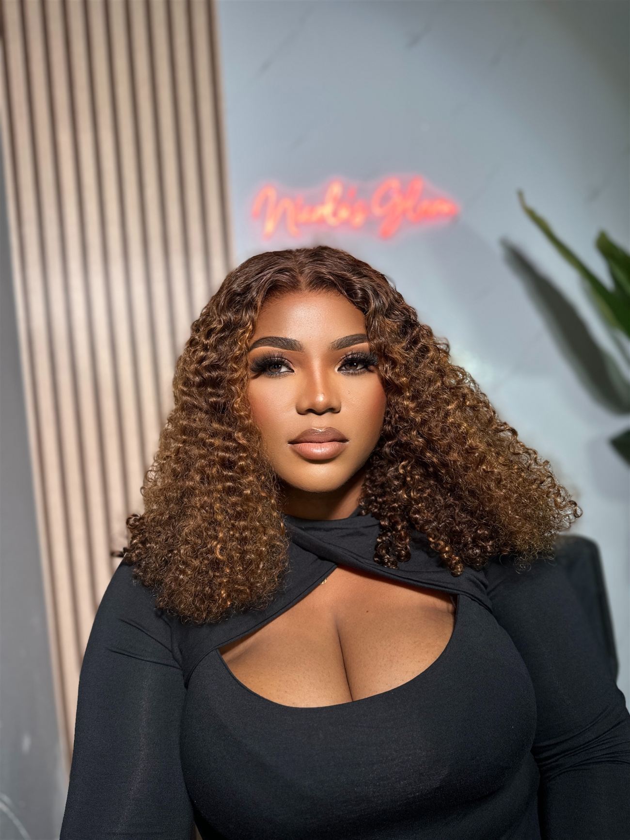 Curly-hair glam under the studio neon sign